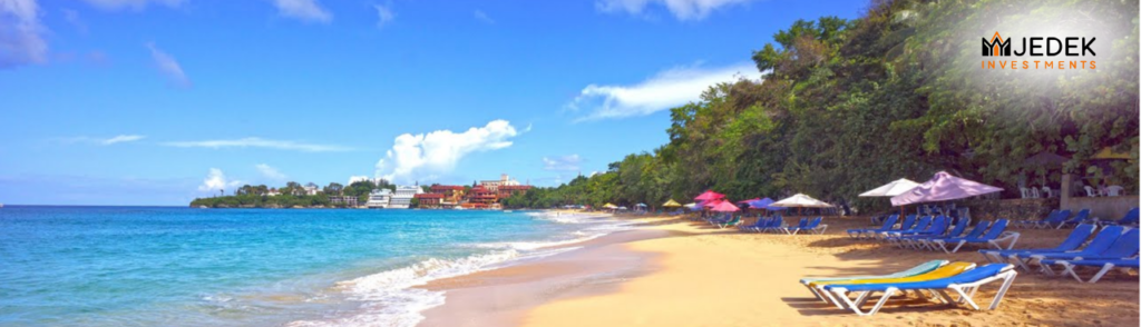 A picturesque view of Sosúa Beach with clear turquoise waters, golden sand, and lush greenery in the background.